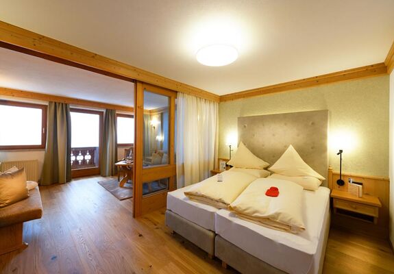 Tweepersoonsbed in hotelkamer met zithoek en balkon