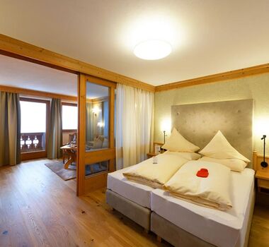 Manželská postel v hotelovém pokoji s posezením a balkonem