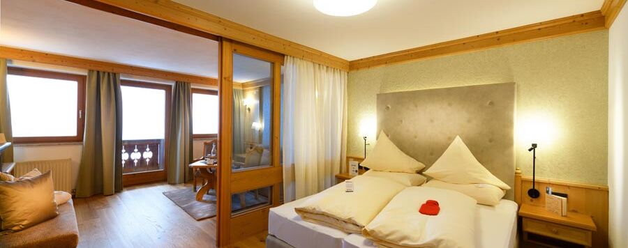 Tweepersoonsbed in hotelkamer met zithoek en balkon