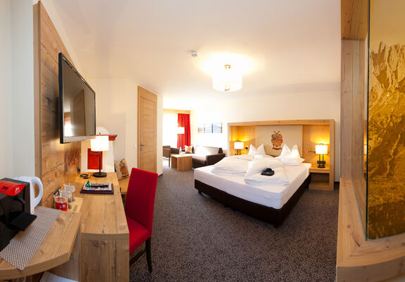 Glance into the Panorama Suite Stefanie with a comfortable bed, a large room and modern interior