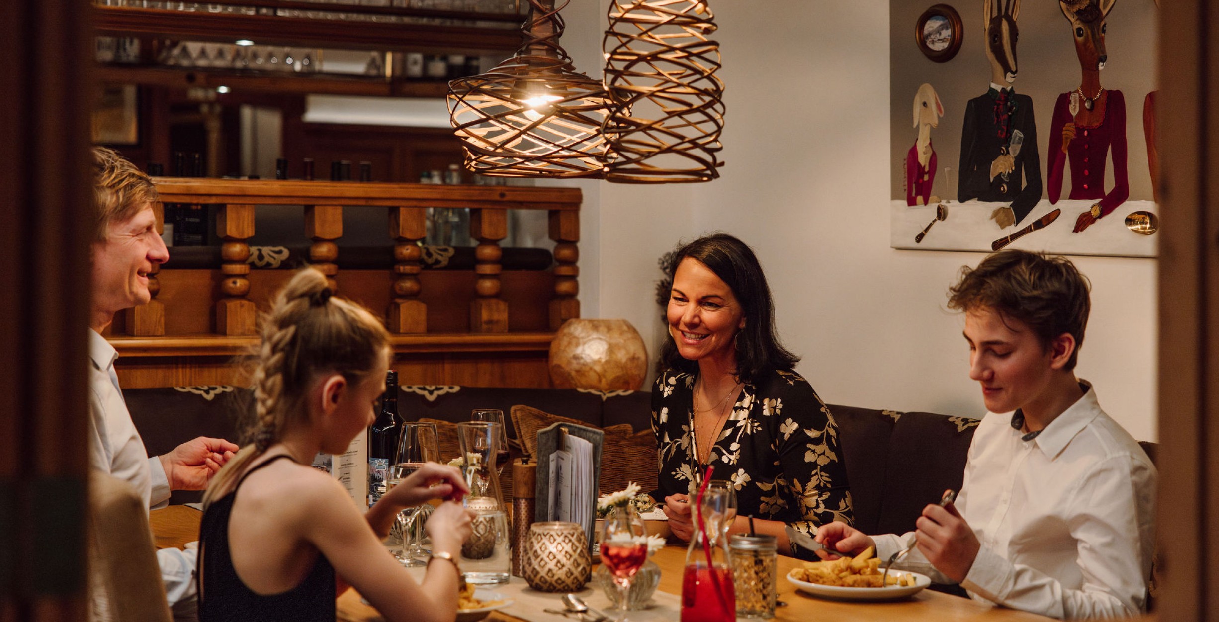 Familie sitzt beim Abendessen in einer gemütlichen Ecke im Hotel Bergheimat