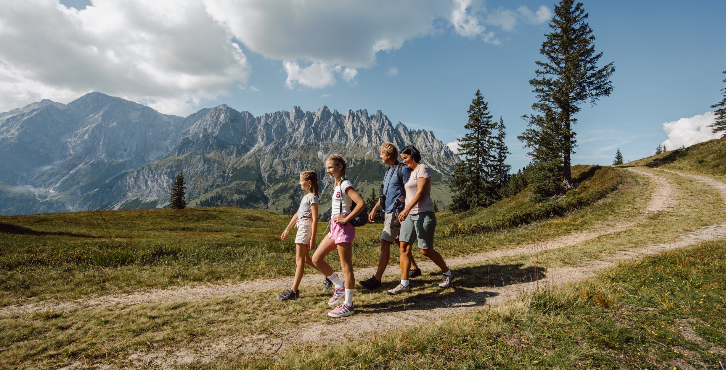 Familie auf 4 Personen geht einen Schotterweg entlang