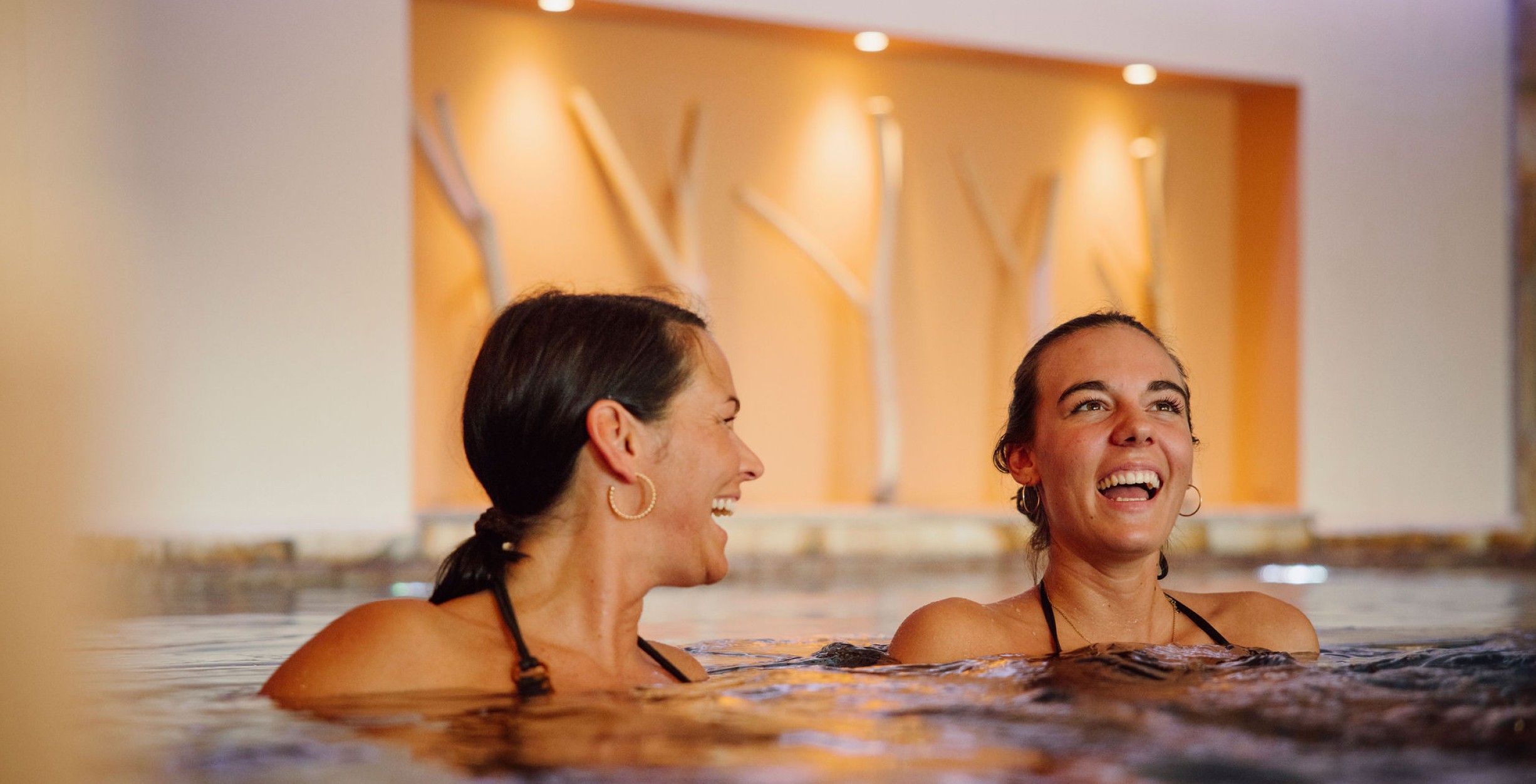Zwei Frauen entspannen im Indoor-Pool des Hotels Bergheimat in Mühlbach am Hochkönig