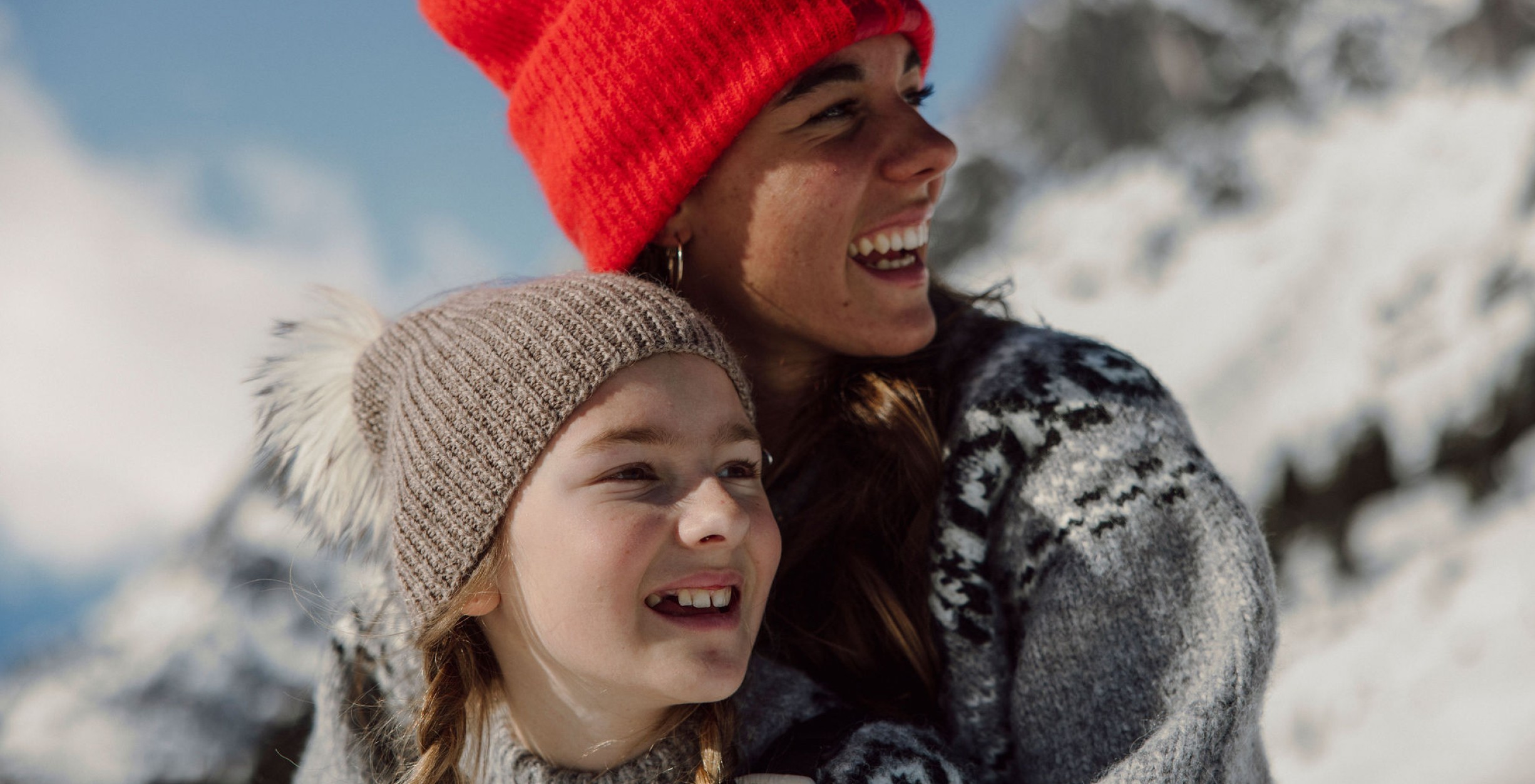 Zwei lächelnde Mädchen mit Mütze im Schnee