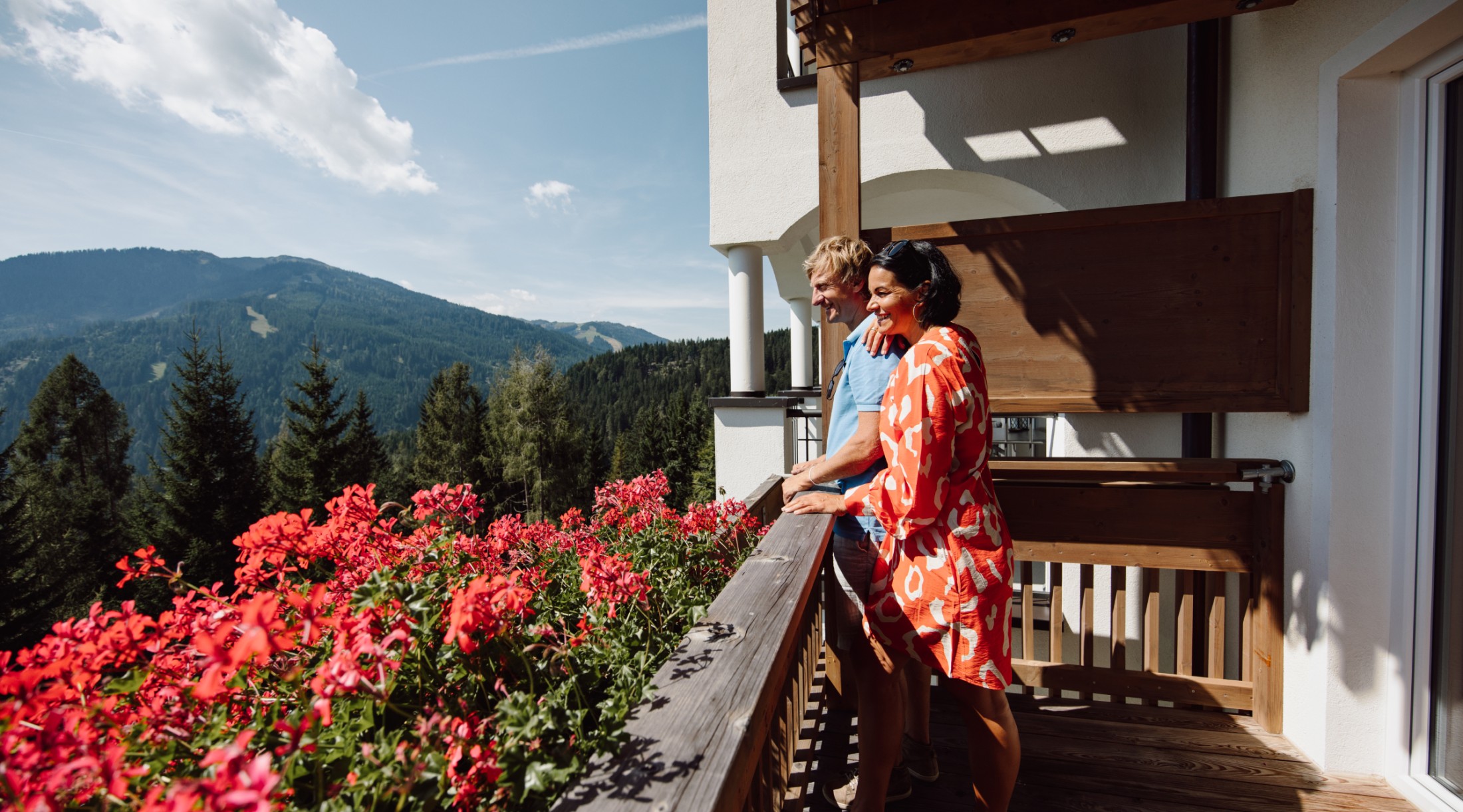 Paar genießt die Aussicht von einem blumengeschmückten Balkon der Bergheimat in Mühlbach