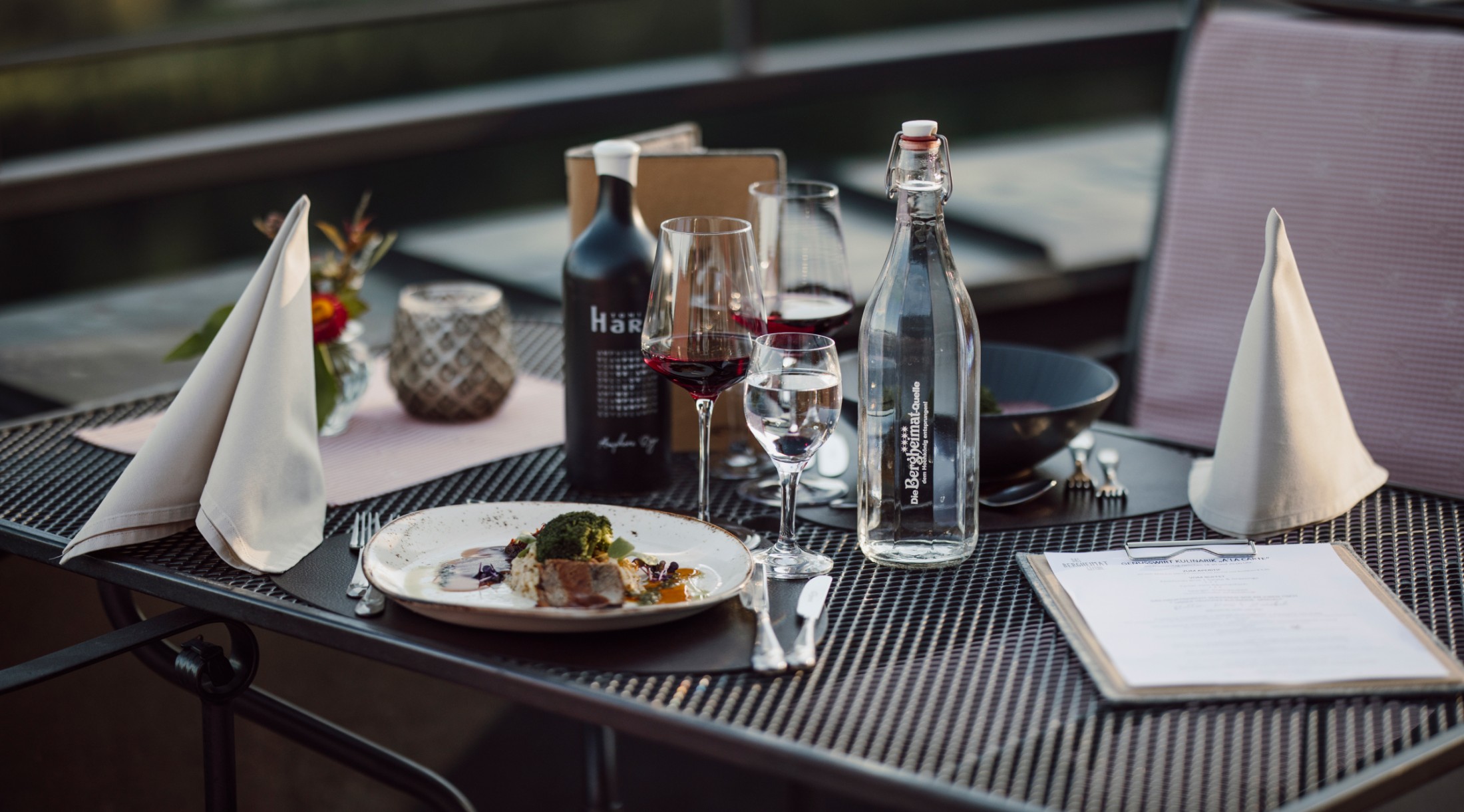 Stilvoll gedeckter Tisch mit Wein und Gourmetgericht auf der Terrasse der Bergheimat