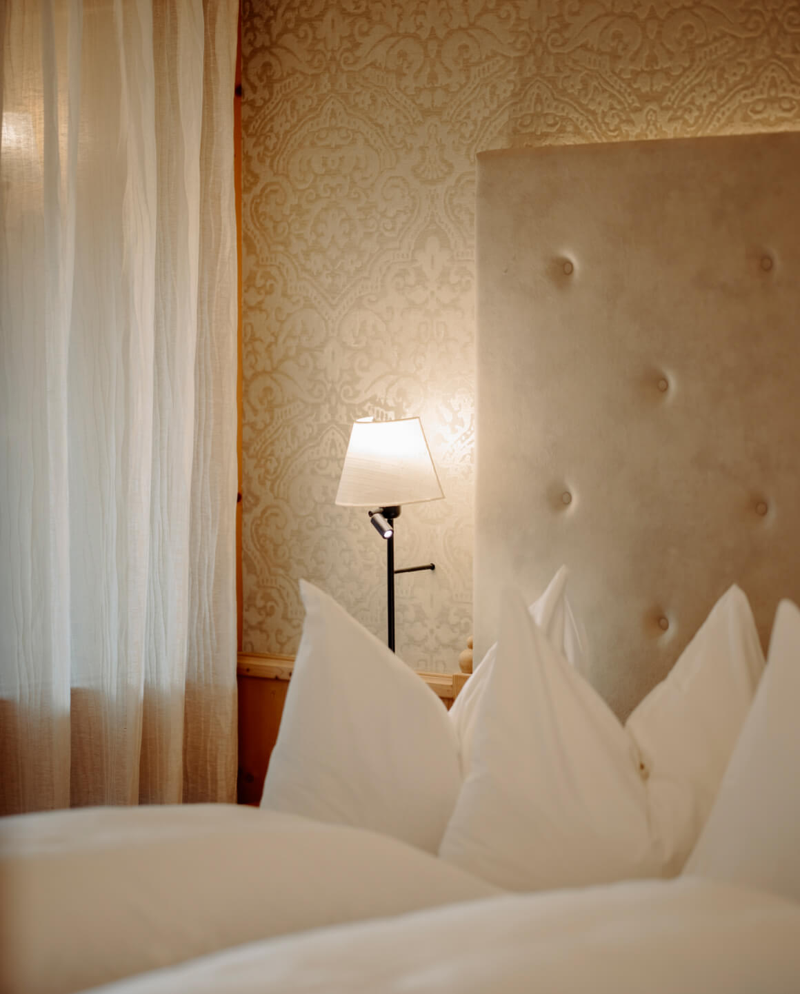 Kuscheliges Bett mit Lampenlicht und eleganter Tapete in der Bergheimat