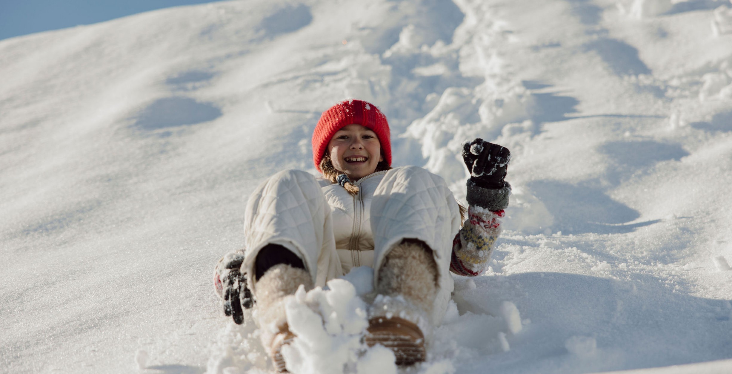 Mädchen rutscht einen Schneehügel herab
