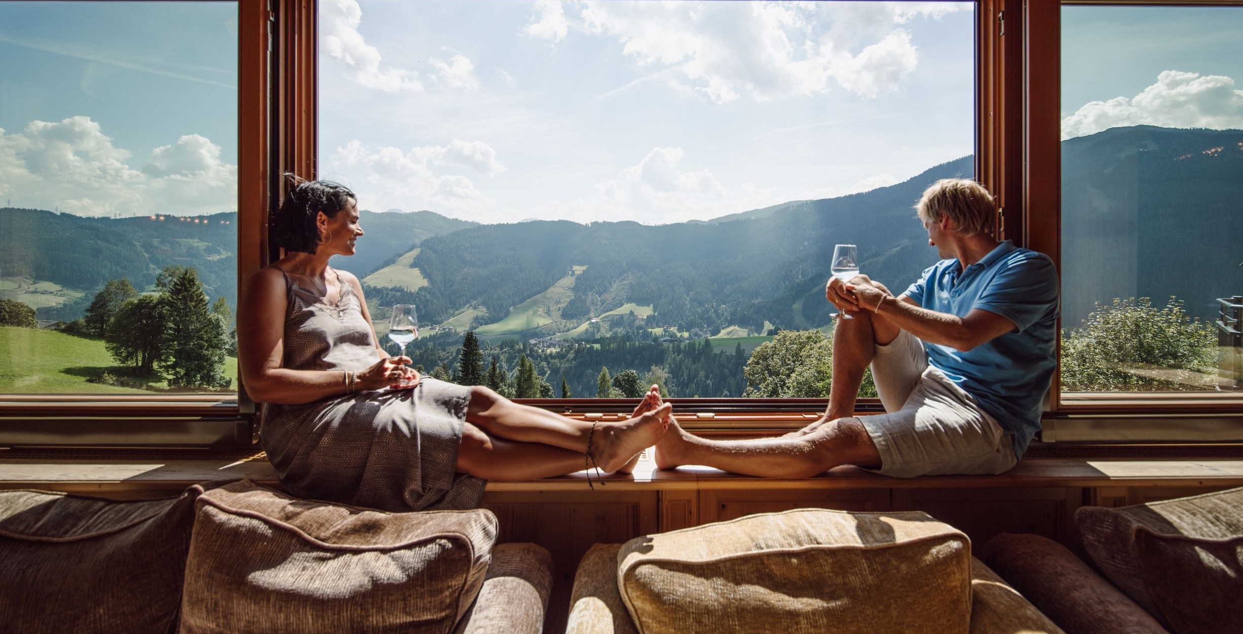 Paar genießt Ausblick vor einem großen Fenster im Hotel Bergheimat