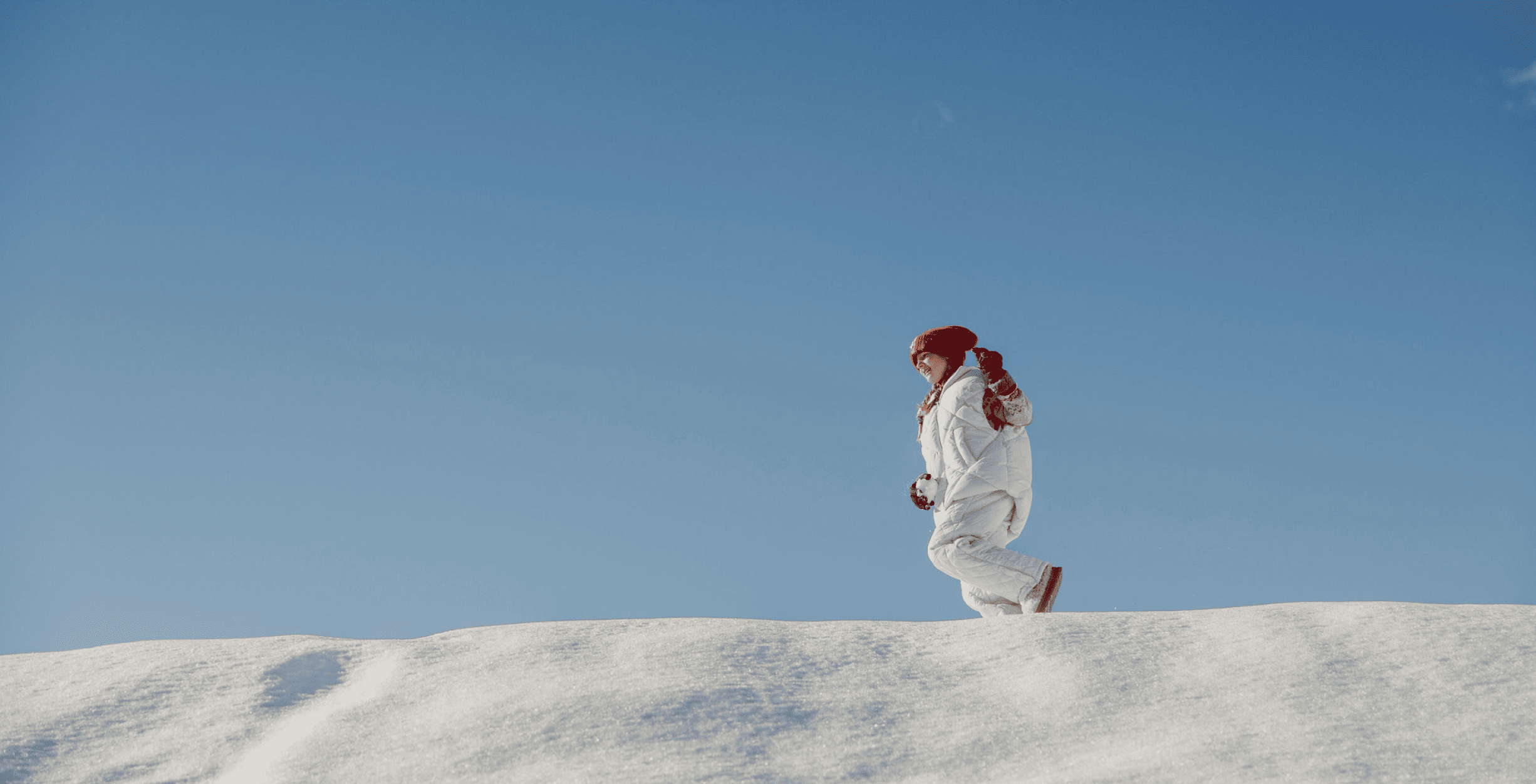 Ein Mädchen spaziert durch den Schnee bei strahlendem Sonnenschein