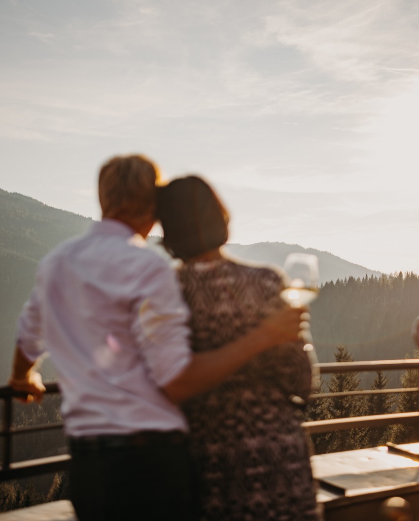 Ein Paar genießt die Abendsonne in der Bergheimat bei einem Glas Wein