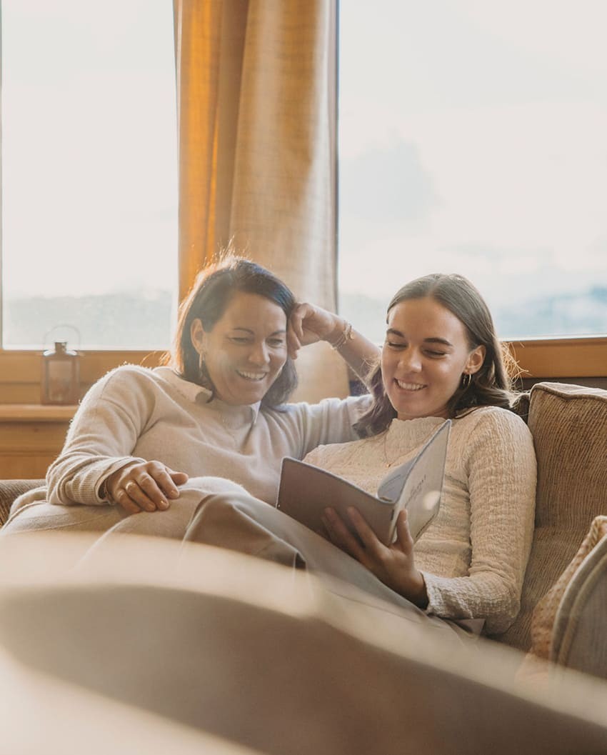 Zwei Frauen entspannen beim Lesen auf dem Sofa in der Bergheimat