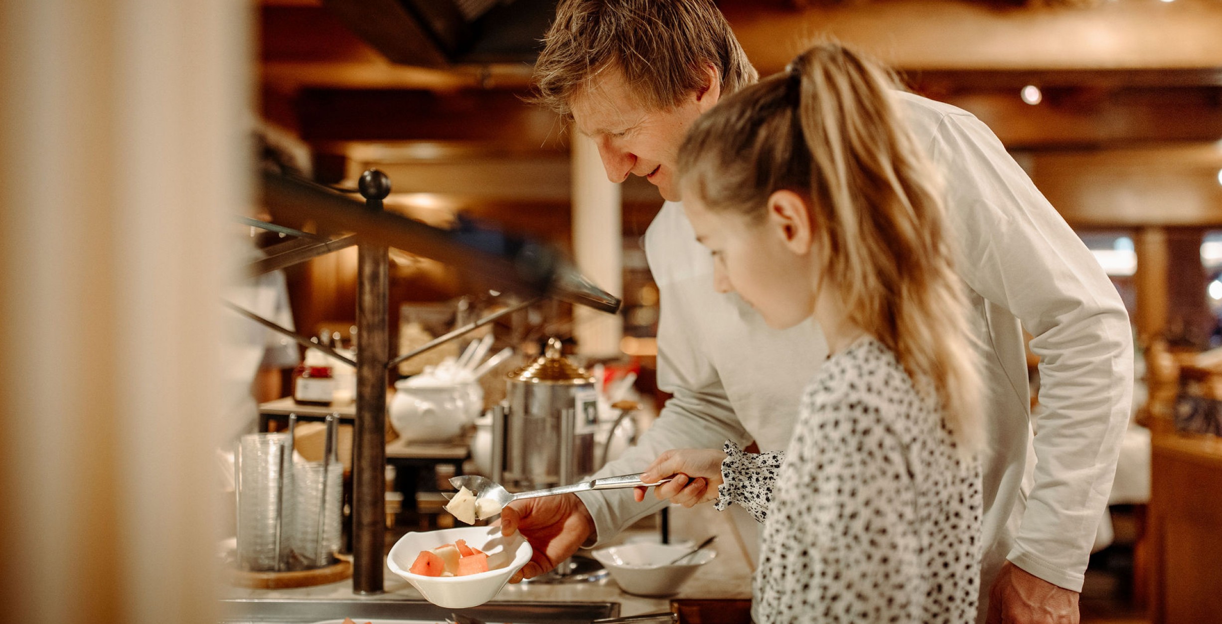 Vater und Tochter bedienen sich am Frühstücksbuffet